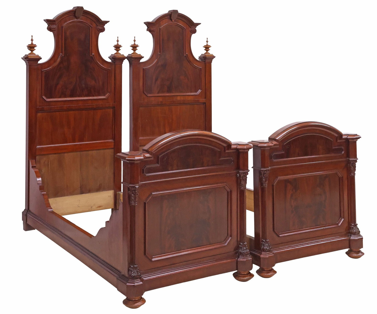 (2) ITALIAN CARVED HIGHBACK MAHOGANY ALCOVE BEDS: (pair) Italian flame mahogany alcove beds, late 19th c., headboard having arch-molded cornice with turned finials, paneled footboard flanked by columnar posts with Corinthian capitals, on flattened bu