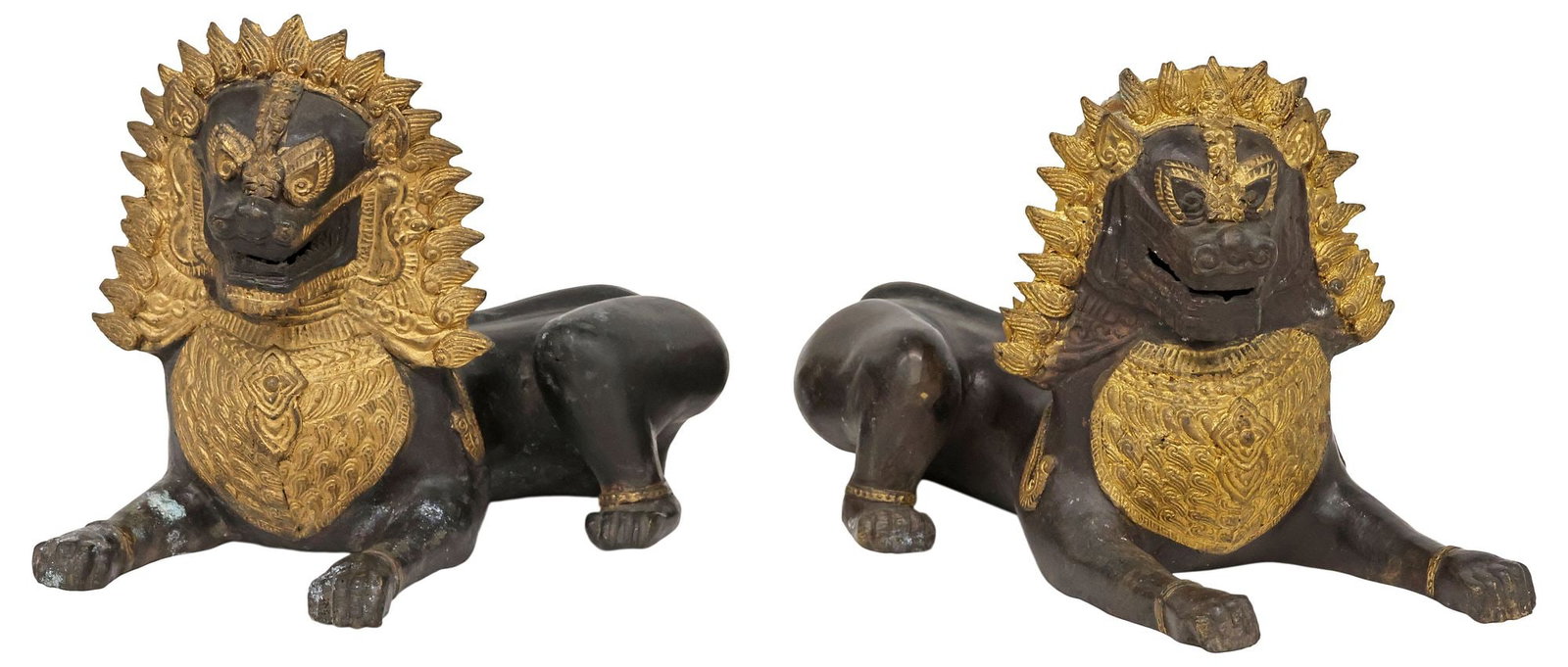 (2) THAI PARCEL-GILT PATINATED BRONZE TEMPLE GUARDIAN SINGHA LIONS: (pair) Southeast Asian parcel-gilt patinated bronze singha temple guardians, Thailand, modeled an opposing pair of recumbent lions with bared fangs, approx 7.75"h, 12"w, 6"d, 12.25lbs total **Provenan