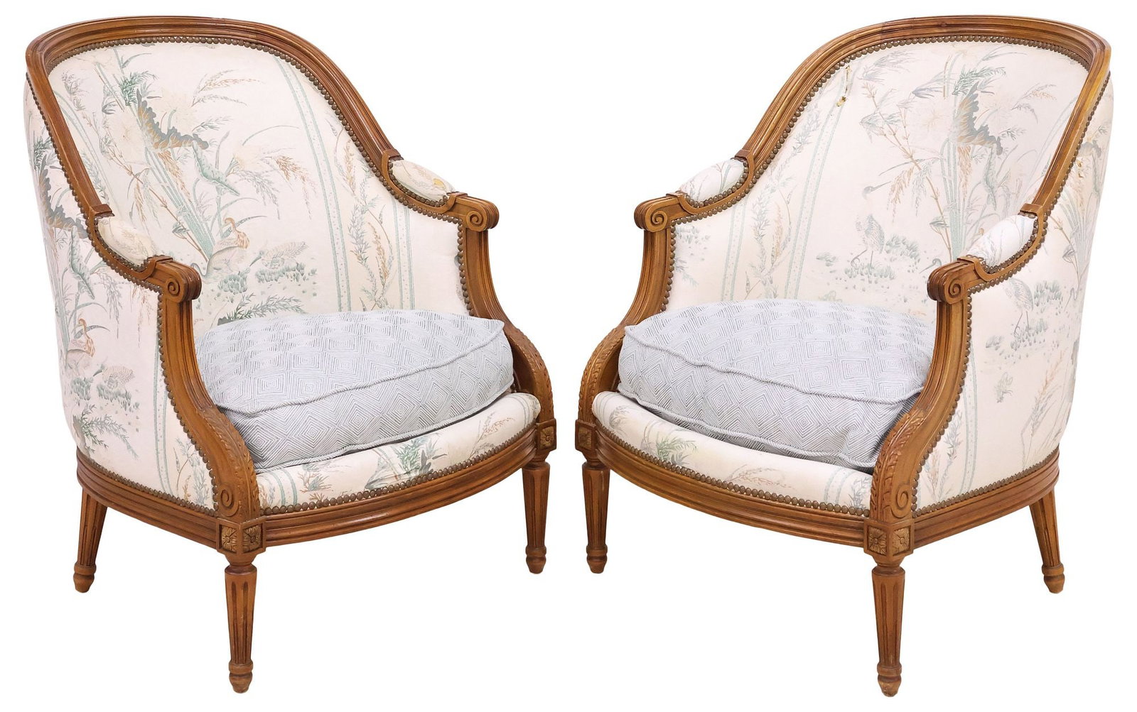 (2) JEAN ROCHE FRENCH LOUIS XVI STYLE UPHOLSTERED BERGERES / ARMCHAIRS: (pair) French Louis XVI style carved wood bergeres/ armchairs, Jean Roche, late 20th c, curved back and padded arms in a worn fabric upholstery, with seabirds amongst vegetation, removable seat cushio