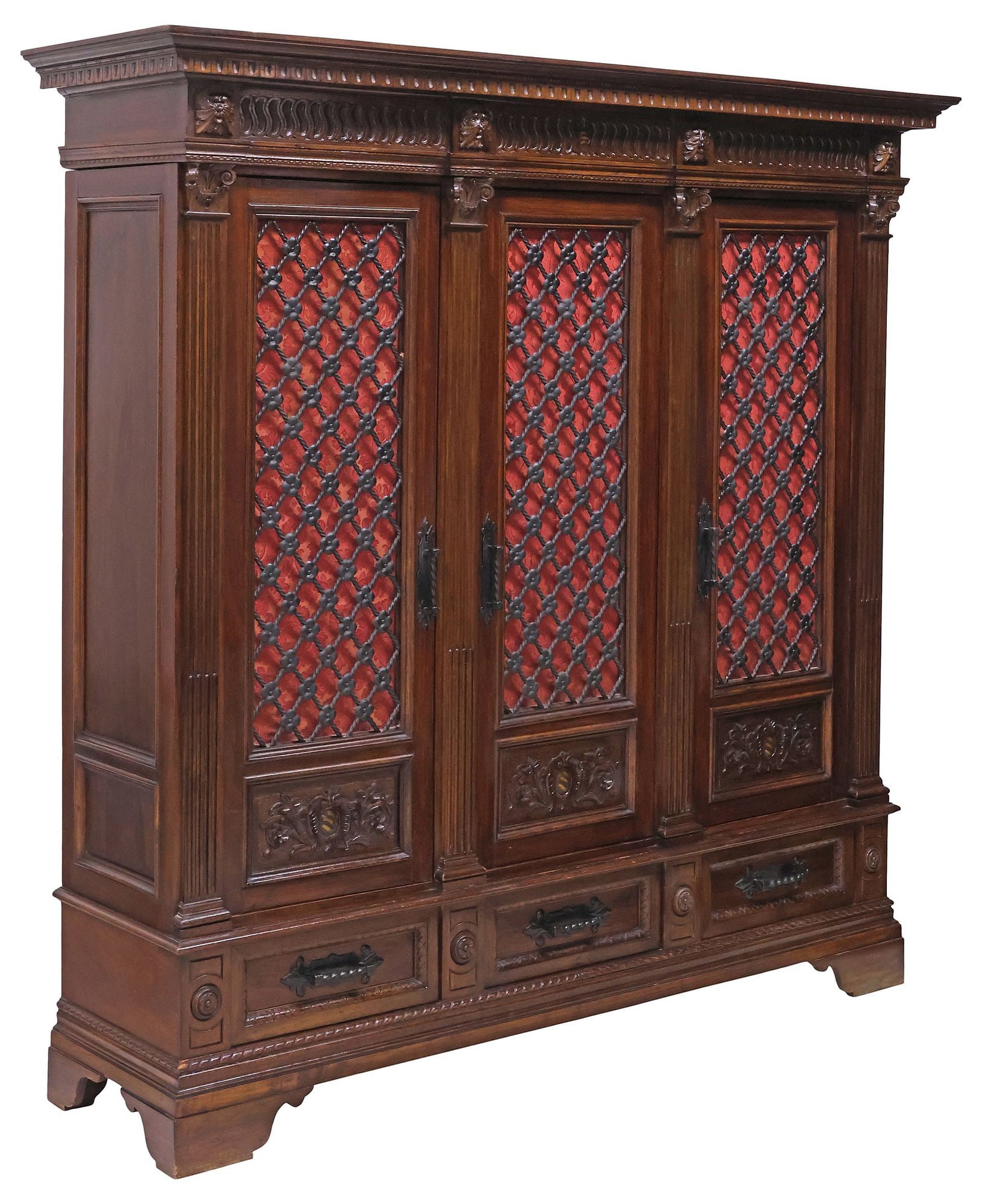 ITALIAN RENAISSANCE REVIVAL CARVED WALNUT & WROUGHT IRON BOOKCASE: Italian Renaissance Revival walnut bookcase, early 20th c., molded cornice and paneled frieze with grotesque masks, over three latticed wrought iron doors with damask fabric lining, framed by