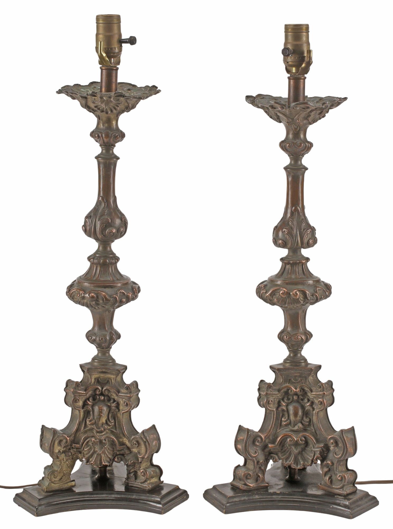 (2) BAROQUE STYLE PATINATED METAL CANDLE PRICKET-FORM 1-LT TABLE LAMPS: (pair) Baroque-style patinated metal candlestick-form table lamps, each having single light, above turned-form standard, rising on tripartite base with repousse scrollwork, observed operating, approx