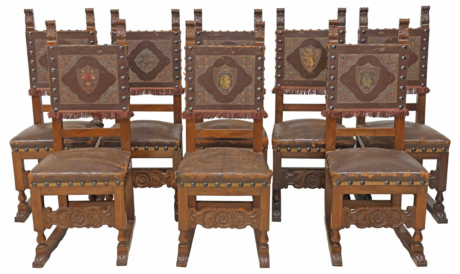 (8) ITALIAN RENAISSANCE REVIVAL EMBOSSED LEATHER & WALNUT DINING CHAIRS: Italian Renaissance Revival walnut dining chairs, late 19th c., each back in an embossed leather upholstery, each with a varied parcel-gilt and painted heraldic shield, later applique fringed trim, pa