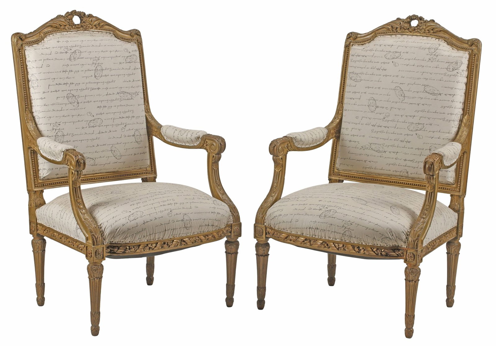 (2) LOUIS XVI STYLE ARMCHAIRS IN CALLIGRAPHIC SCRIPT-PRINTED UPHOLSTERY: (pair) Louis XVI style parcel-gilt wood armchairs/ fauteuils, early 20th c., each in a faux leather upholstery with printed calligraphic script and letter stamps, rising on tapering fluted legs, endin