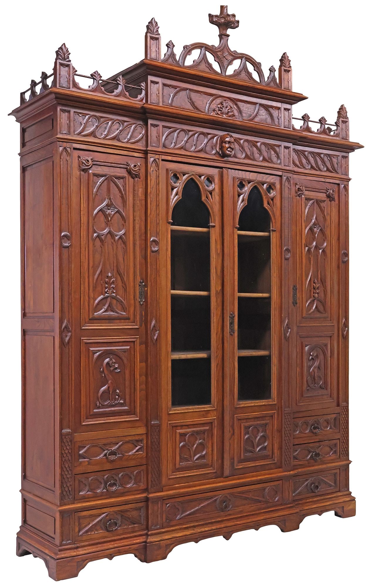 FINE FRENCH GOTHIC REVIVAL CARVED OAK BREAKFRONT BOOKCASE, 115.5"H: French Gothic Revival carved oak bookcase, late 19th c., having pierced tracery gallery with central flame-form finial, over pair of centered glazed cabinets, flanked by single cabinet with mythical b