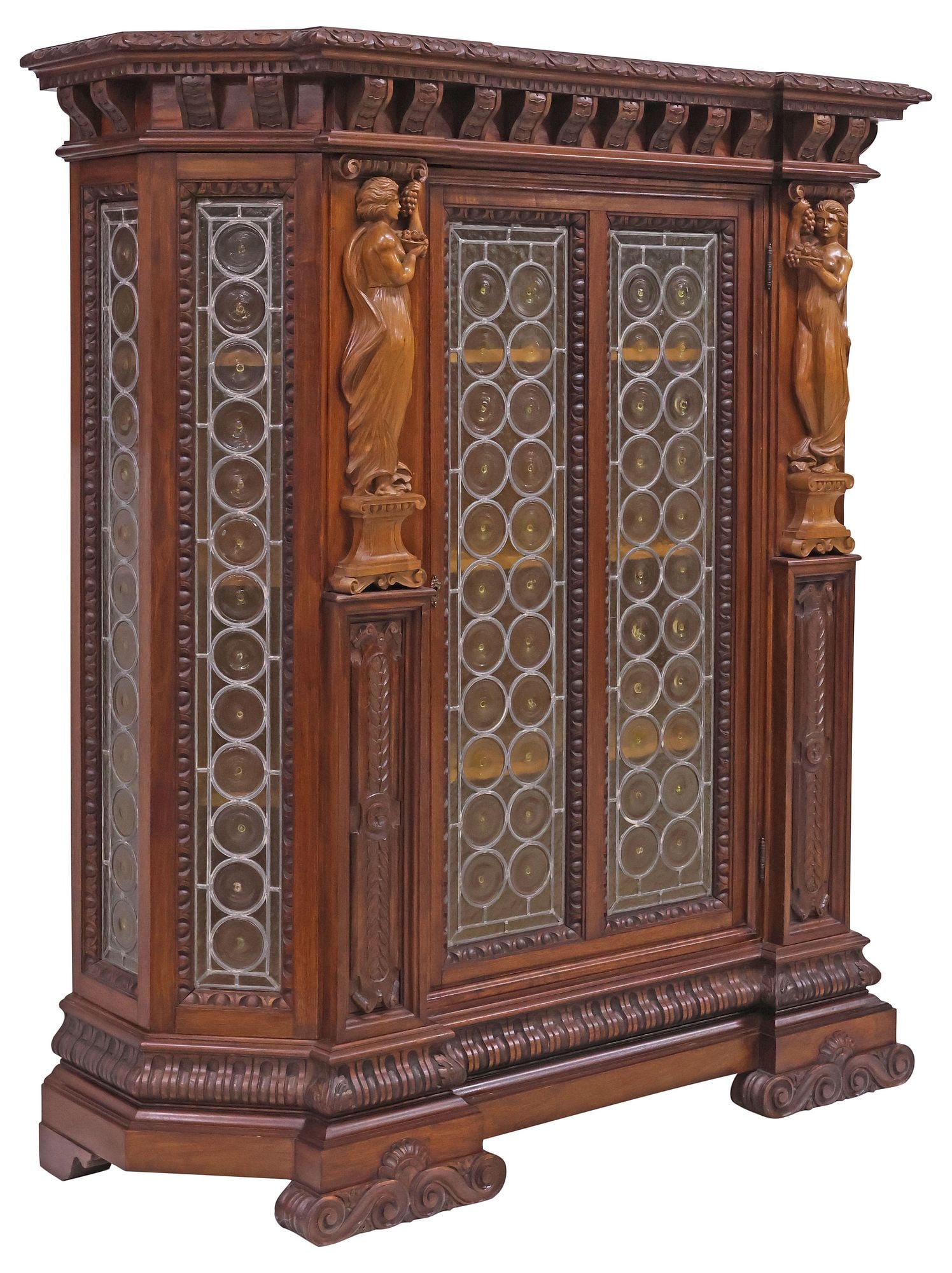 ITALIAN RENAISSANCE REVIVAL CARVED WALNUT & LEADED GLASS BOOKCASE: Italian Renaissance Revival carved walnut bookcase or cabinet, early 20th c., shaped case with foliate-molded cornice, over single door and sides encasing colorless leaded bullseye glass, flanked by f