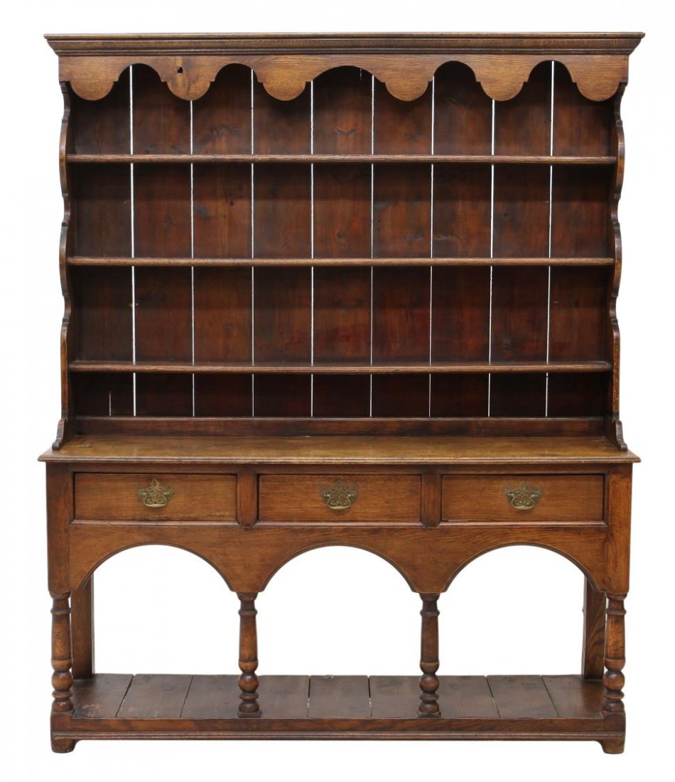 BRITISH OAK WELSH DRESSER, 18TH C.: British Welsh dresser, 18th c., the oak structure in two-parts, projected cornice above shaped crest, plank back panel and shelving, the base fitted with three aligned drawers, supported on turned leg