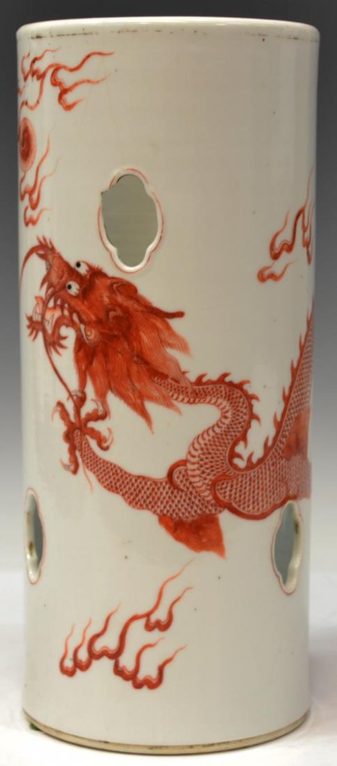 ANTIQUE CHINESE IRON RED DRAGON HAT STAND: Chinese iron red enameled porcelain hat stand, the cylindrical body pierced with lobed openings and painted with a dragon in pursuit of a flaming pearl, late Qing/Republic period, chipping at one pier