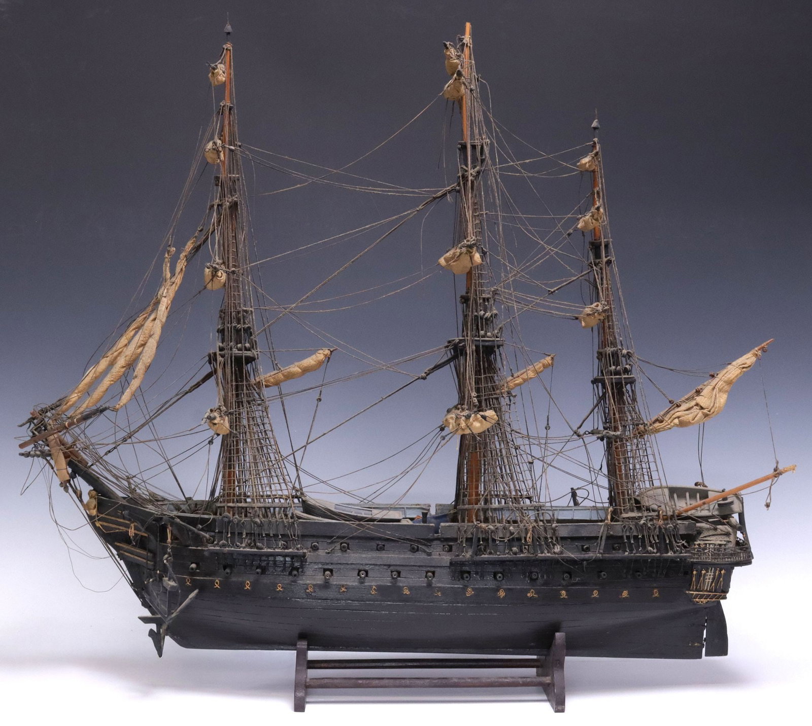 FULLY RIGGED THREE-MAST MODEL SAILING SHIP WITH STAND, 26"H: Large model sailing ship, 20th c., three-masted single hull vessel with cannons, tied fabric sails, and corded rigging, accompanied by display stand, some typical loss to rigging, approx 26.25"h, 29"w
