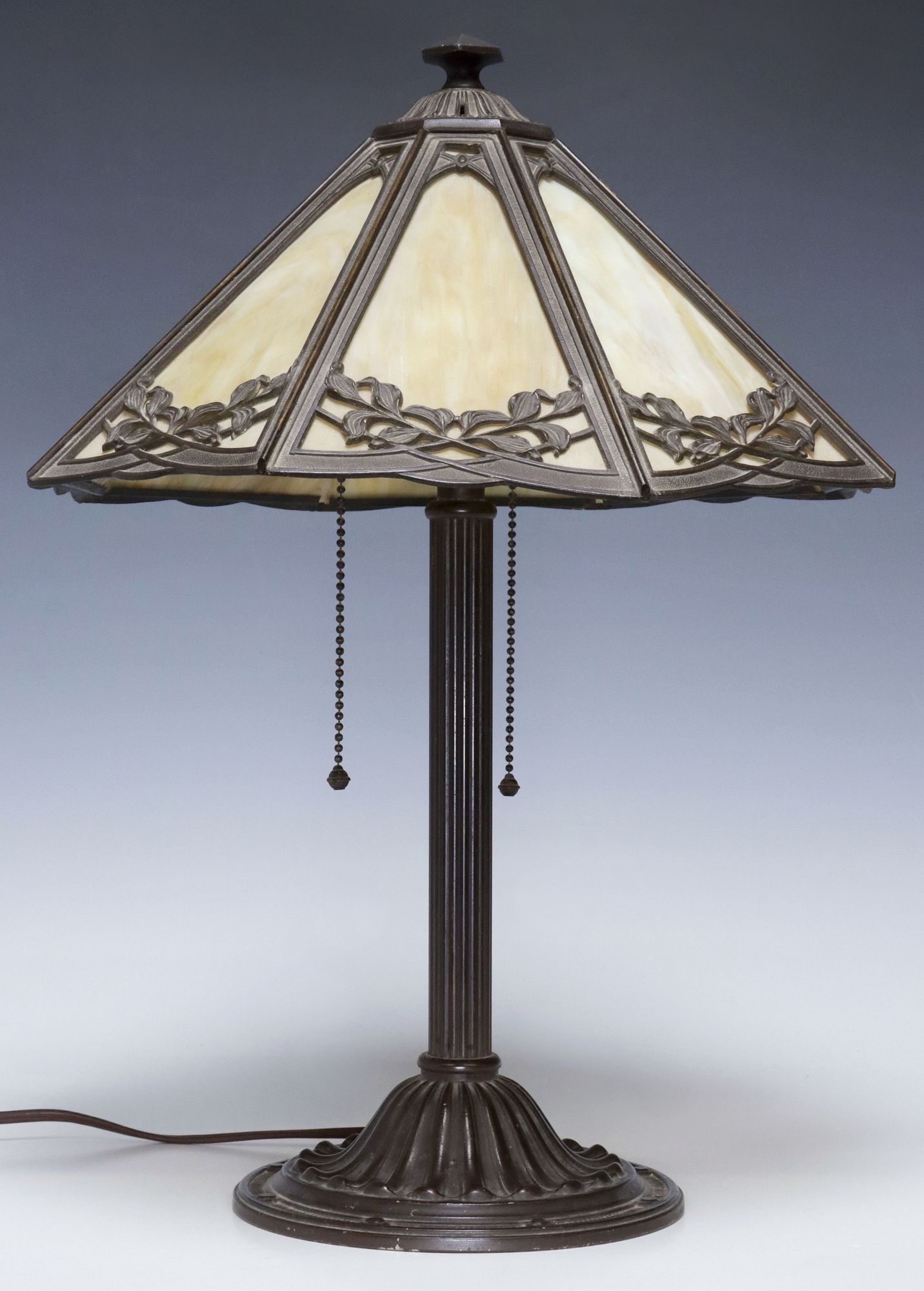 AMERICAN SLAG GLASS & PATINATED METAL 2-LIGHT TABLE LAMP: American slag glass two-light table lamp, early 20th c., octagonal shade with inset glass panes, geometric and foliate overlay, rising on fluted standard, over ribbed base, observed operating, lamp: a