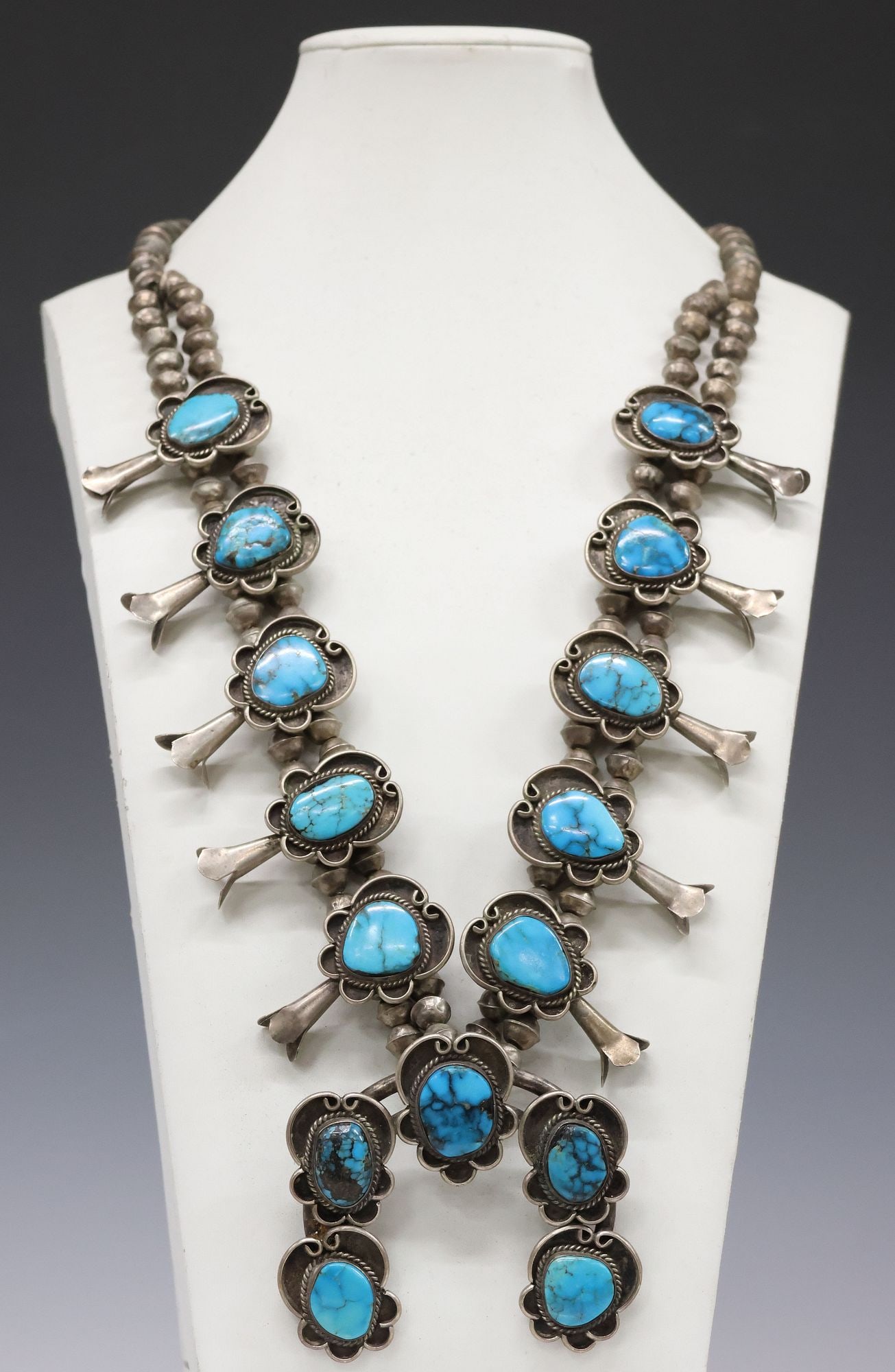 NATIVE AMERICAN SILVER & TURQUOISE CABOCHON SQUASH BLOSSOM NECKLACE: Native American silver (content unknown) and turquoise squash blossom necklace, large split-band naja pendant with five cartouche-shaped plaques, each with bezel-set turquoise cabochon in twisted rope
