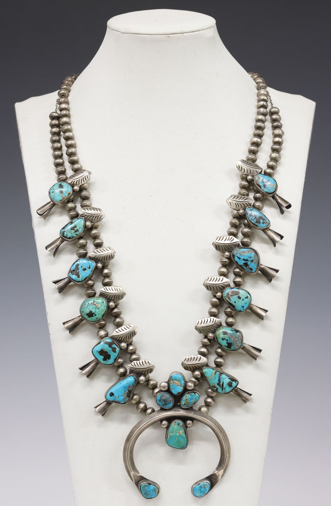 L. BENALLY NAVAJO SILVER & TURQUOISE SQUASH BLOSSOM NECKLACE: Native American silver (content unknown) and turquoise squash blossom necklace, L. Benally (Navajo/ Dine, 20th c.), semicircular naja pendant with six bezel-set turquoise cabochons, framed by (twelve)