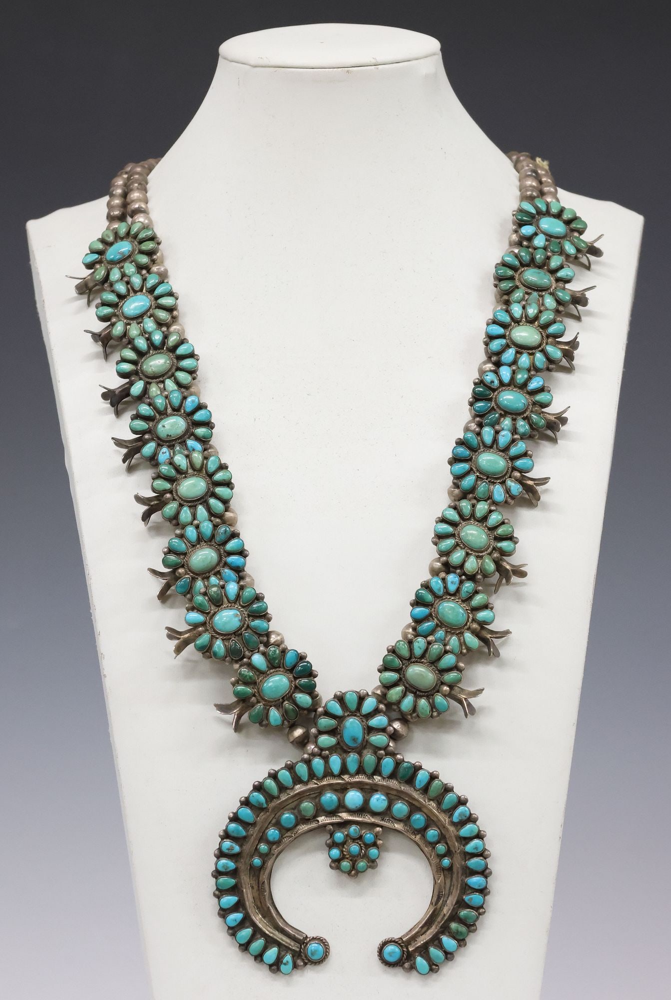 FINE ZUNI PETIT-POINT TURQUOISE & SILVER SQUASH BLOSSOM NECKLACE: Fine Native American silver (content unknown) and turquoise squash blossom necklace, likely Zuni Pueblo, large petit-point naja pendant with radiating turquoise cabochons, beaded trim and stampwork mo
