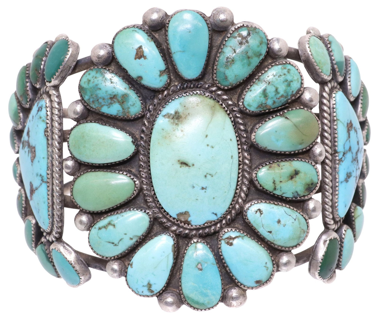 LARGE NATIVE AMERICAN SILVER & TURQUOISE CLUSTER CUFF BRACELET: Native American silver (content unknown) cuff bracelet, split shank with central floriform bezel-set with (fifteen) turquoise cabochons, encircled by spacer beads and rope trim, flanked by half-moon s