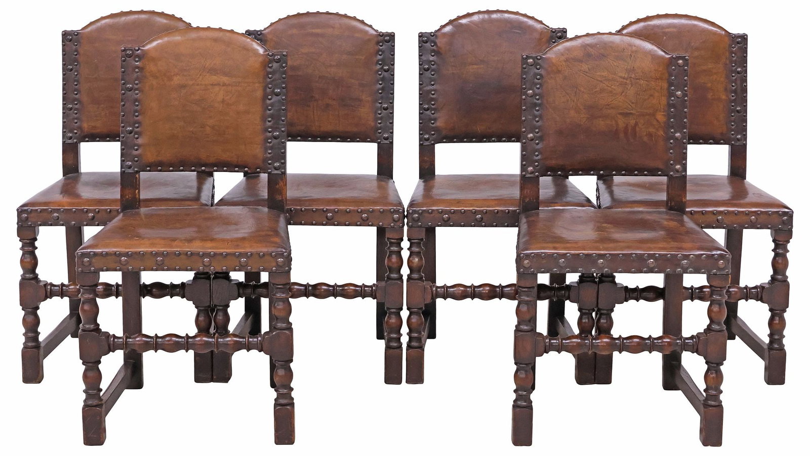(6) ENGLISH JACOBEAN REVIVAL LEATHER & OAK DINING CHAIRS: (lot of 6) English Jacobean Revival oak dining chairs, early 20th c., arched backs and seats in a brown leather upholstery, with nail-head trim, rising on turned legs, ending on stretcher-joined block