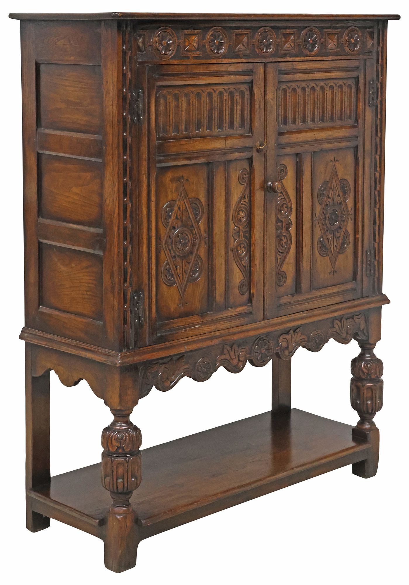 ENGLISH JACOBEAN STYLE CARVED OAK CUPBOARD CABINET: English Jacobean style oak cupboard/ cabinet, early 20th c., having rectangular top, over pair of paneled cabinet doors on iron hinges with carved geometrics and floral medallions, enclosing fixed-hei
