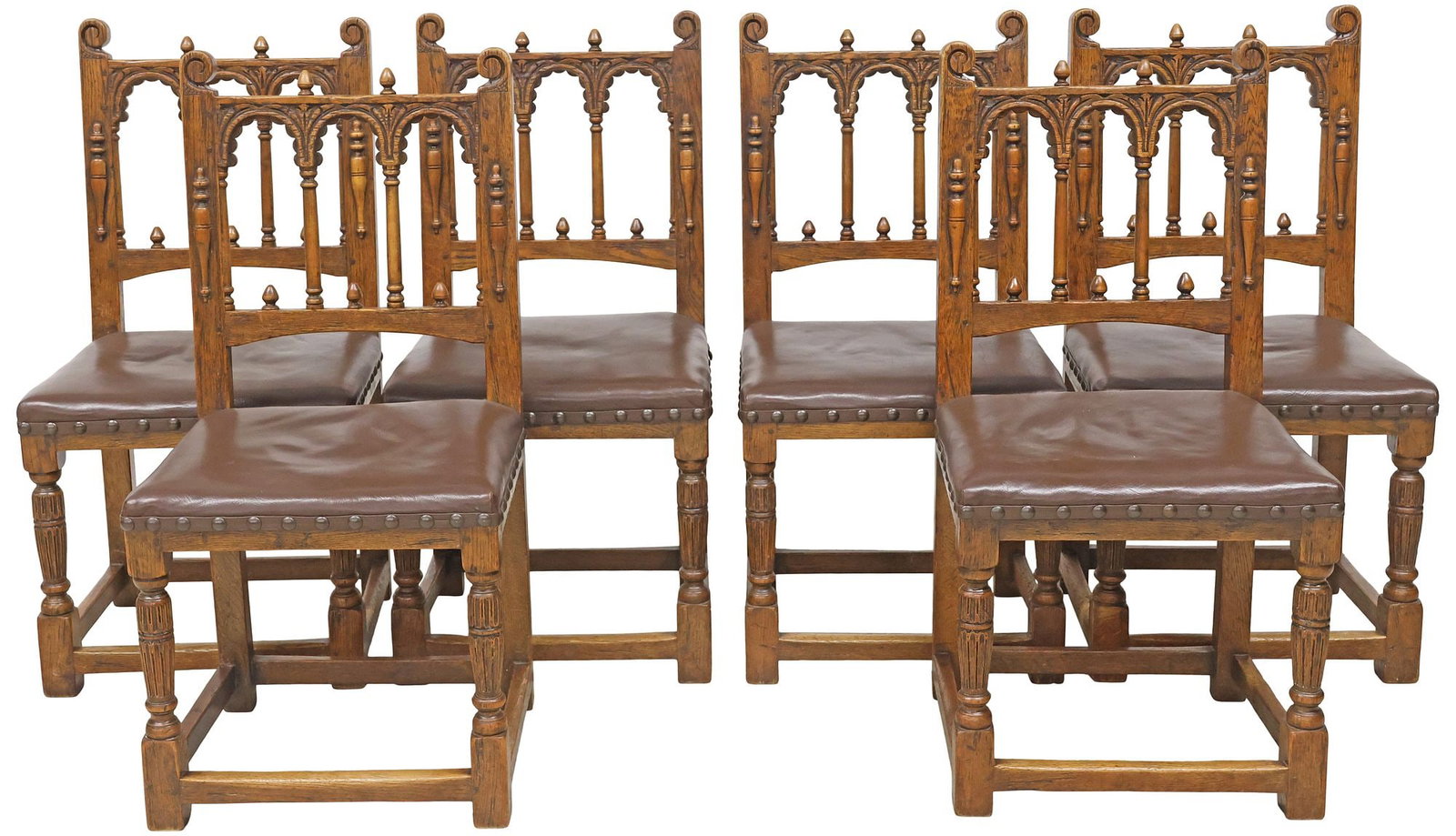 (6) ENGLISH GOTHIC REVIVAL CARVED OAK & LEATHER DINING CHAIRS: (lot of 6) English Gothic Revival oak dining chairs, early 20th c., having arcaded backs with columnar supports and scrolled stiles, padded seat in a brown leather upholstery, nail-head trim, raised o