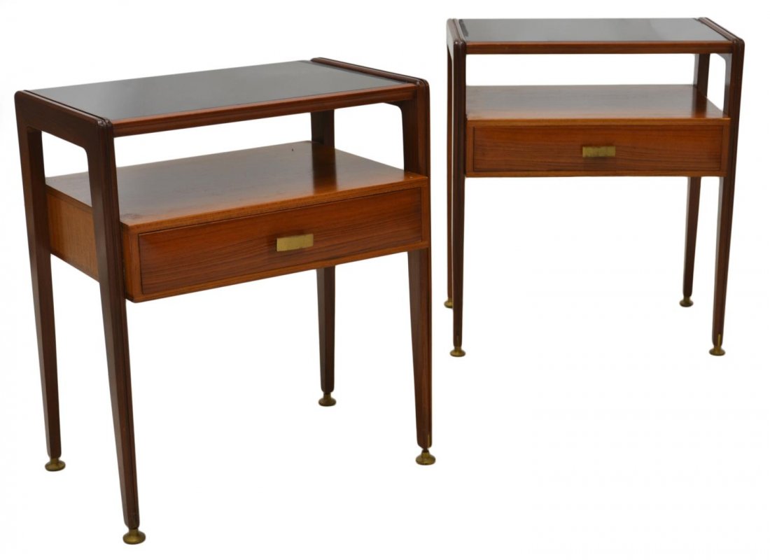 ITALIAN MID-CENTURY GLASS TOP TEAKWOOD SIDE TABLES: (pair) Italian mid-century modern teakwood side tables, c. 1950's / 60's, each having black glass top, single drawer with gilt metal hardware, tapered legs end in gilt disc feet, approx 21.75"h, 12.75