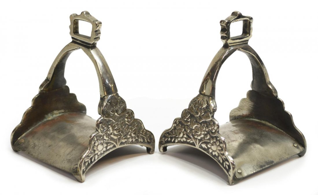 (PAIR) ANTIQUE FLORAL MOTIF SILVERPLATE STIRRUPS: (pair) Antique Spanish-style silver plate on copper stirrups, sprouted flower decor to either side of the arched frame, hammered rivet joinery to base as pictured, 7"h, 4.75"w, 4.5"d, 2.75lbs total *P