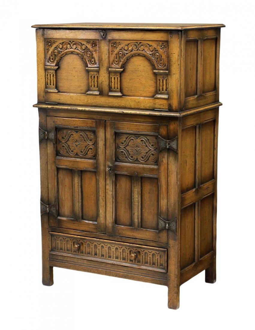JACOBEAN STYLE CARVED OAK BUTLERS CHEST: Jacobean style carved oak butlers chest, floral carved arches on the fall front upper section, opening to storage, a pair of doors below conceal three drawers with gilt hardware, all above a single, s