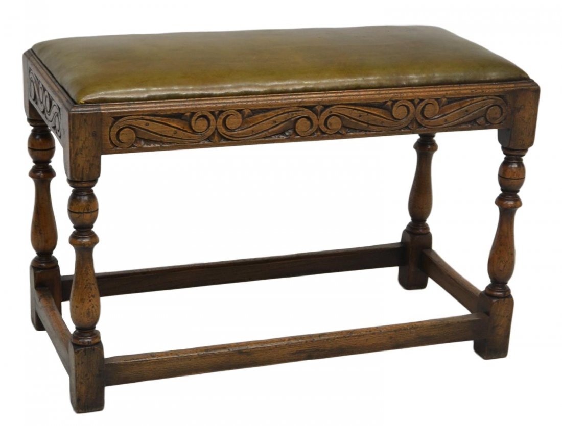 ENGLISH STYLE UPHOLSTERED CARVED OAK BENCH: English style oak bench with upholstered cushion, foliate carving on the oak frame rising on stretcher joined turned legs with block feet, 18.5"h, 28"w, 13.5"d *Provenance: The estate of Douglas B. Ma