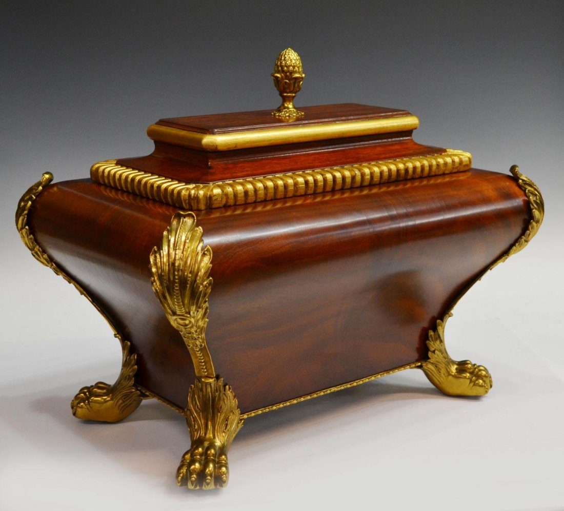 MAITLAND SMITH MAHOGANY SARCOPHAGUS FORM CASK: Large Maitland Smith mahogany cask, the oversized box of sarcophagus form having parcel gilt hinged lid surmounted pineapple finial, by a , heavy gilt brass foliated mountings terminate in well define