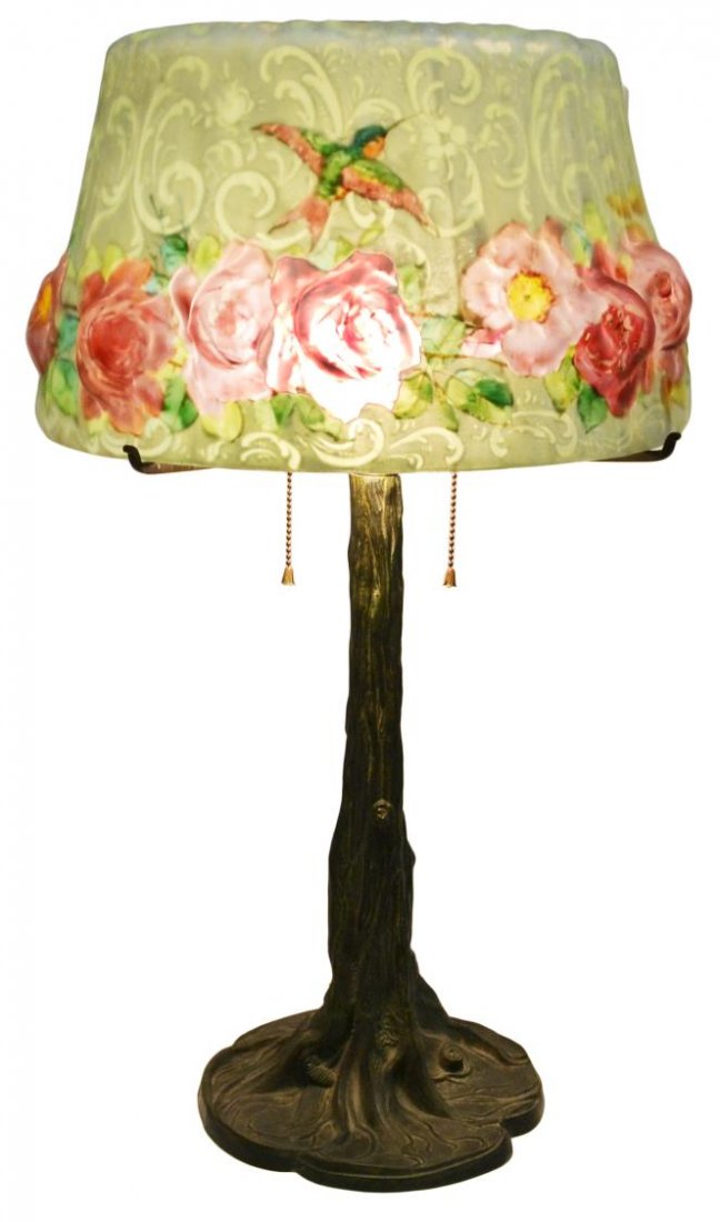 PAIRPOINT PUFFY TWO-LIGHT HUMMINGBIRD TABLE LAMP: Pairpoint puffy two-light table lamp, the Stratford glass shade reverse painted with roses under flying hummingbirds on a scrolling foliate and frosted ground, rising on a tree trunk form base, marked
