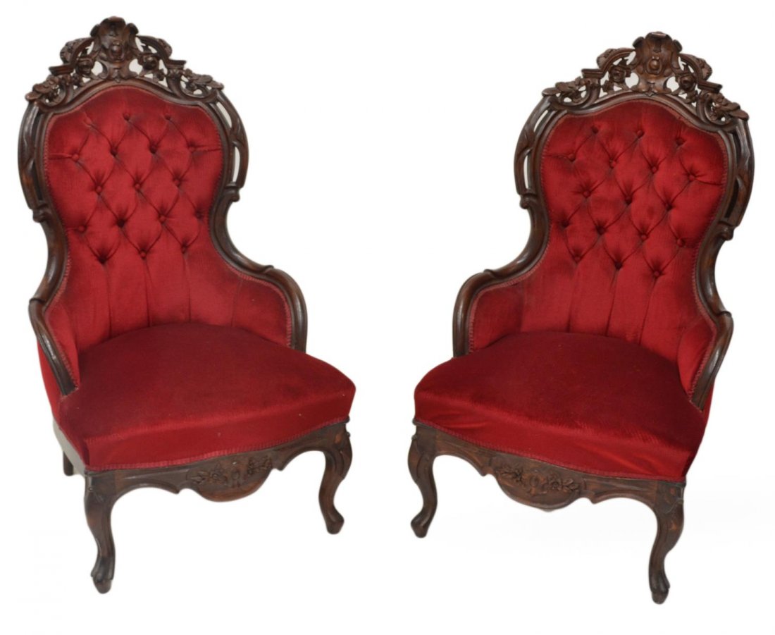 (PAIR) ANTIQUE ROCOCO CARVED TUFTED PARLOR CHAIRS: (pair) Victorian style upholstered arm chairs, early 20th c., in the Rococo manner, floral carved and pierced crest over the ruby red buttoned back, rising on cabriole supports, 43"h, 24.5"w, 28"d Sta