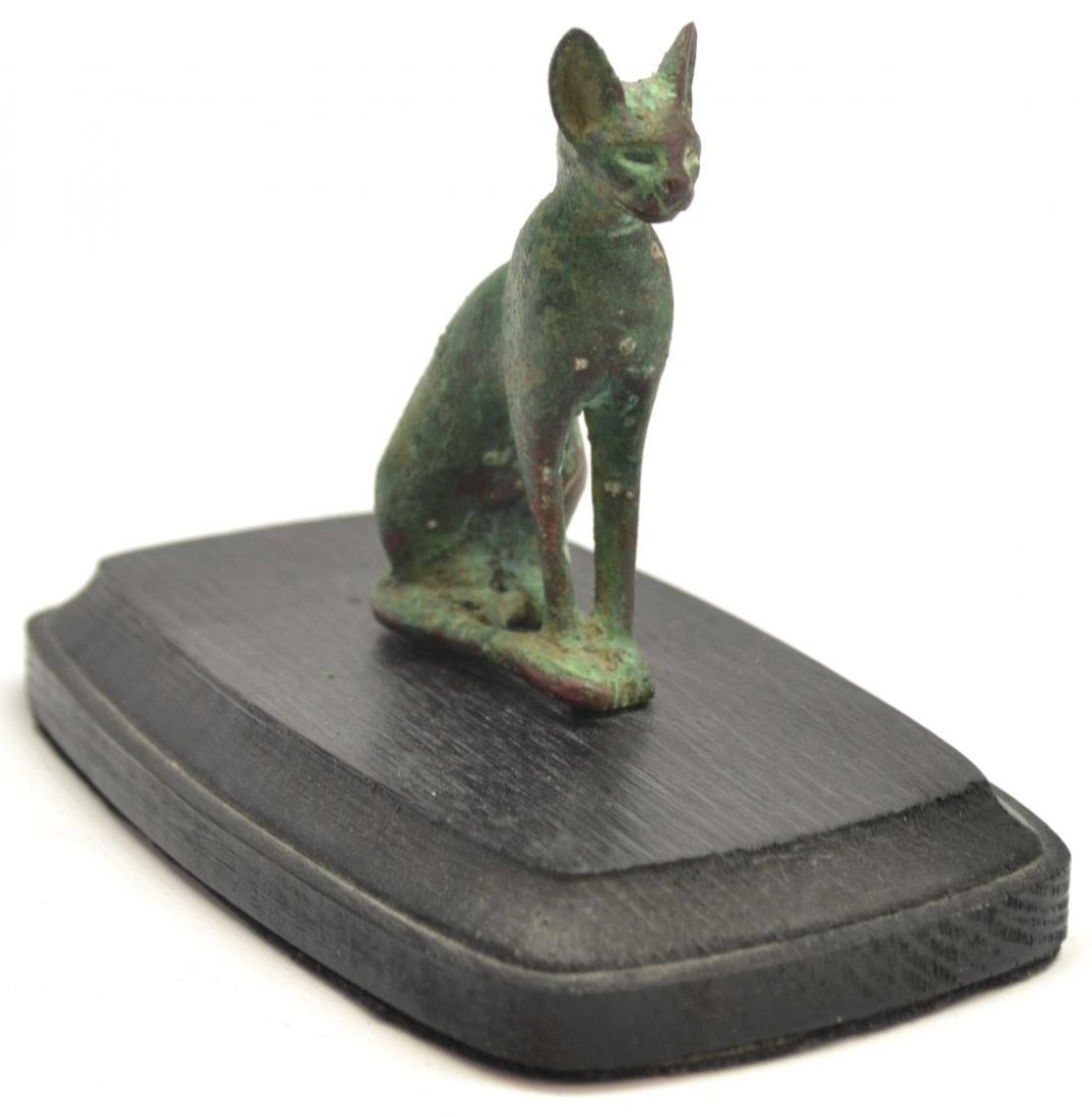 ANCIENT EGYPTIAN BRONZE CAT, CIRCA 600 B.C.E.: Egyptian bronze cat, a depiction of the Goddess Bastet, late Saite period (664-554 B.C.E.), green patina with reddish brown bronze areas, later wood stand, 3.5"h inclusive of integral bronze tenon, .5