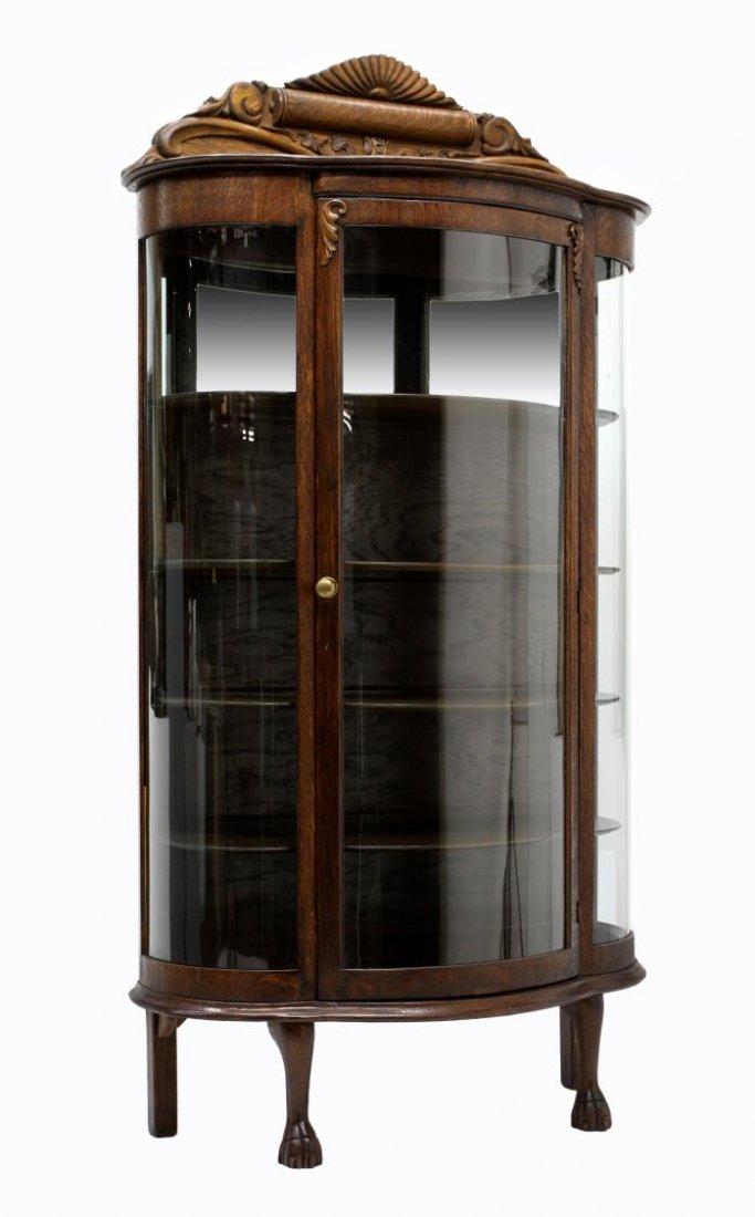 AMERICAN OAK CURVED GLASS CHINA CABINET: American quarter sawn oak display cabinet, c. 1900, a central cornice with applied carving over the curved glass door and sides, the interior with partial mirror back, four adjustable wood shelves, al