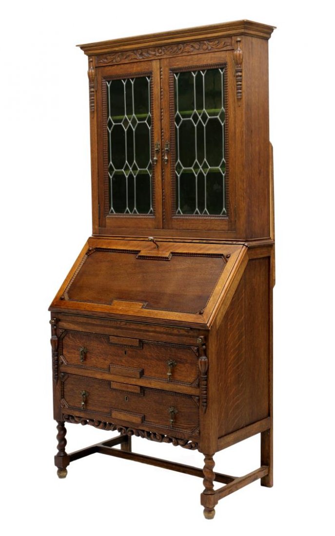 LEADED GLASS OAK SECRETARY BOOKCASE: Oak secretary bookcase, England, c. 1910, a stepped cornice over two glazed leaded glass doors open to book shelves, a slant front bureau opens to writing surface, two lower drawers, all raised on twi