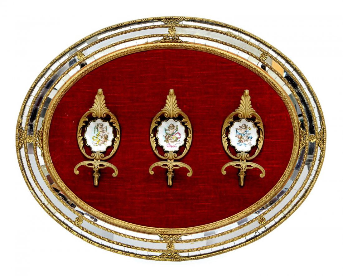 SPAIN GILTWOOD & MOSAIC MIRROR HANGING COAT RACK: Continental giltwood hanging coat rack, Spain, three gilt metal hooks centered by winged cherub plaques on a red velvet ground, the oval gilded form having mirrored mosaic borders, applied with gilt m