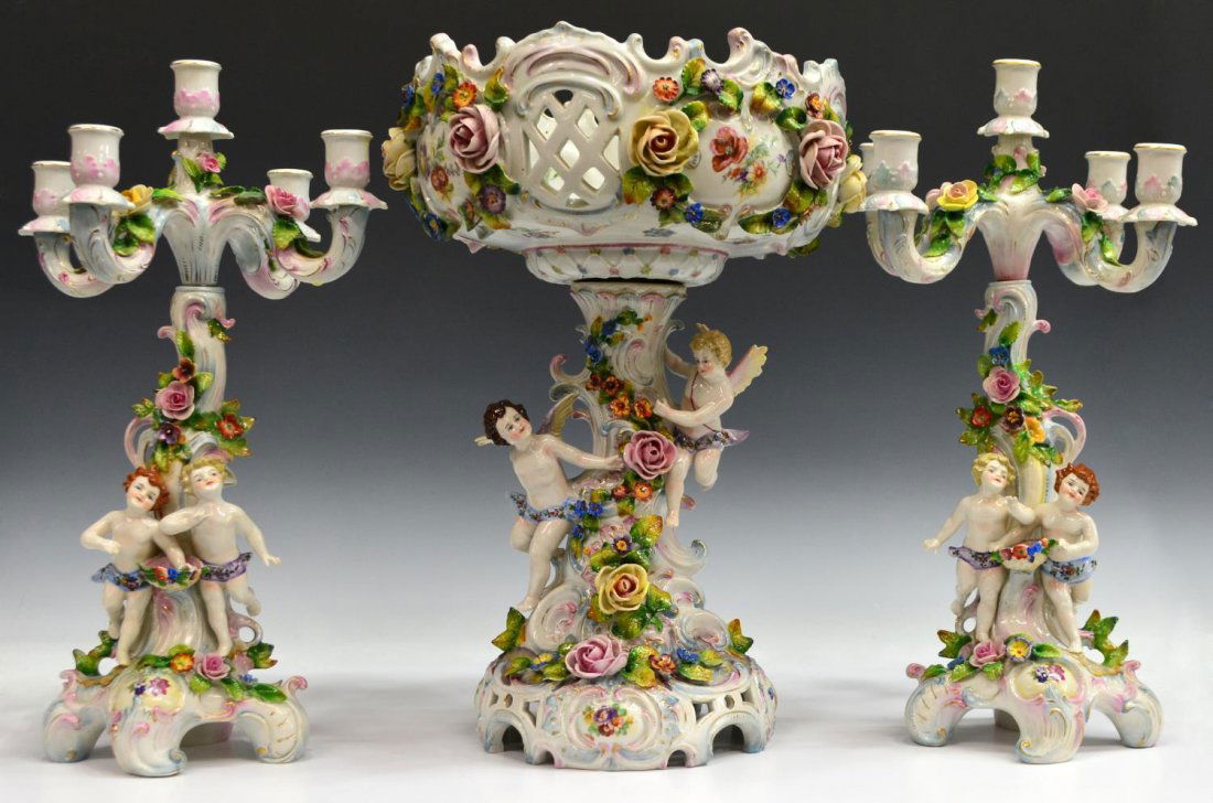 (3) DRESDEN STYLE PORCELAIN CHERUB GARNITURE SET: (set of 3) German porcelain garniture set, L & R Germany, in the Dresden style with applied putto and flowers, comprising: (1) centerpiece, rocaille borders on the reticulated bowl, applied flowers an