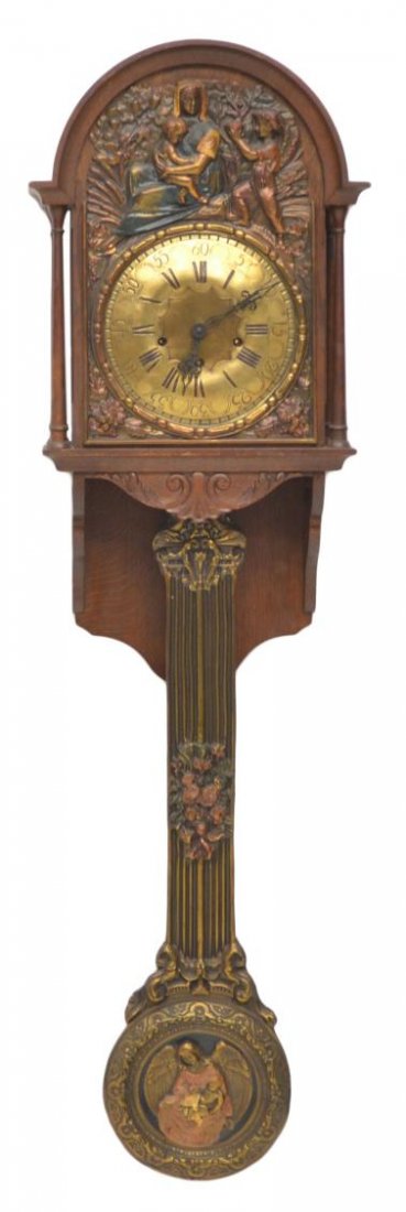 MORBIER STYLE OAK & GILT METAL CLOCK, WINGED ANGEL: Morbier style chiming time and strike wall clock, the arched oak top with repousse polychrome metal figural scene scene, gilt metal dial with Arabic and Roman numerals, mounted on a carved oak case wi