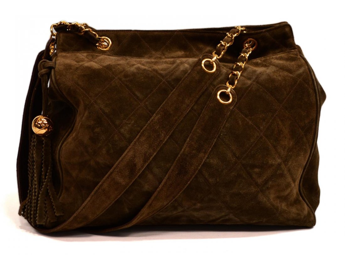 CHANEL BROWN SUEDE QUILTED TOTE BAG, C. 1994: Chanel brown suede quilted tote bag with tassel, c. 1994, having gold tone hardware, two large exterior slip pockets enclose central big with two zipped pockets and open interior, some marks and wear 