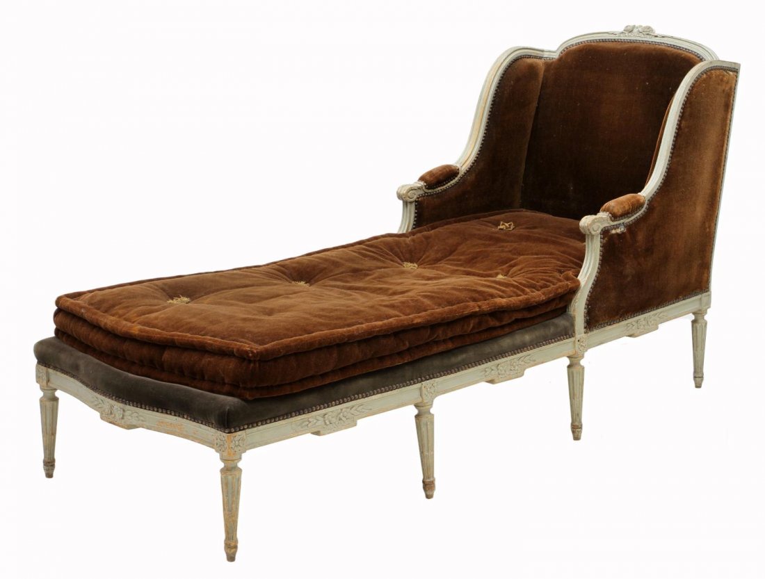 LOUIS XVI STYLE CHAISE LONGUE: Louis XVI style chaise longue, c. 1900, a carved floral crest partial painted frame over the straight back, shaped padded arms terminating in scrolled hand holds, early brown buttoned upholstery, risi