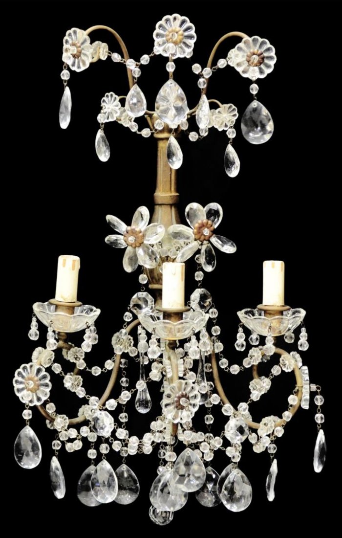 ITALIAN METAL & CRYSTAL THREE-LIGHT WALL SCONCE: Italian metal and crystal three-light wall sconce, early 20th c., the scrolled metal frame hung with colorless swags and prisms, flower head detail throughout, paint loss to candle covers, some flakes