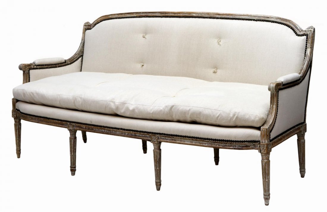 FRENCH LOUIS XVI STYLE UPHOLSTERED SOFA: French Louis XVI style sofa,19th c., upholstered in a later cream color fabric, the parcel white arched frame with padded arms, down cushion, raised on tapered ribbed legs, old beetle damage at unders