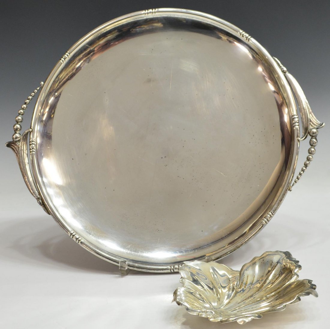 (2) AMERICAN STERLING SILVER SERVICE TRAY & DISH: (lot of 2) American sterling silver table items: (1) Early 20th c. Woodside Sterling Company service tray of circular form, New York, beaded handles join foliated trim, 14.5"diam; (1) Fisher Silversmi