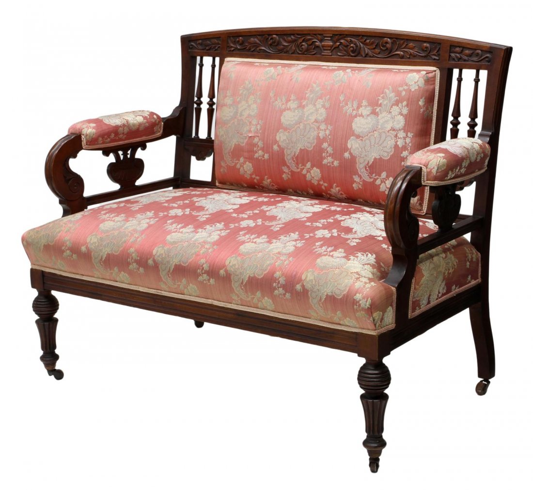 AMERICAN VICTORIAN CARVED SETTEE: American Victorian mahogany settee, late 19th c., foliate carved crest rail with spindle sides flanking the back and seat with recent floral upholstery, padded arms with scrolled hand holds, tapered t