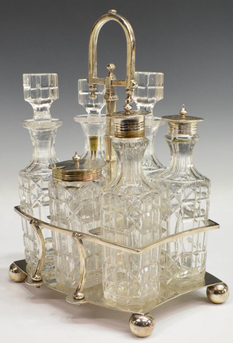 ENGLISH SILVER PLATE & CUT GLASS CASTOR SET: English silver plate caster set, R. Spiller, Islington, six glass bottles with cut glass designs, fitted in a handled and shaped stand, set on four ball feet, hallmarked R. Spiller 166 Upper Street Is