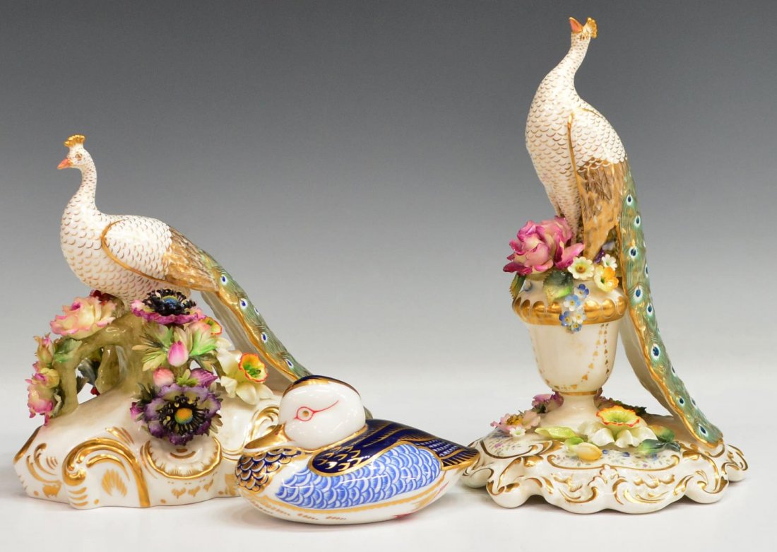 (2) ROYAL CROWN DERBY PEACOCKS & DUCK FIGURE: (3) Royal Crown Derby bird statues: (2) parcel gilt, modeled as a peacock with long tail feathers, (1) perched upon a floral encrusted urn and base with gilded accents, approx 9.25"h, 5.75"w, 5.5"d, (