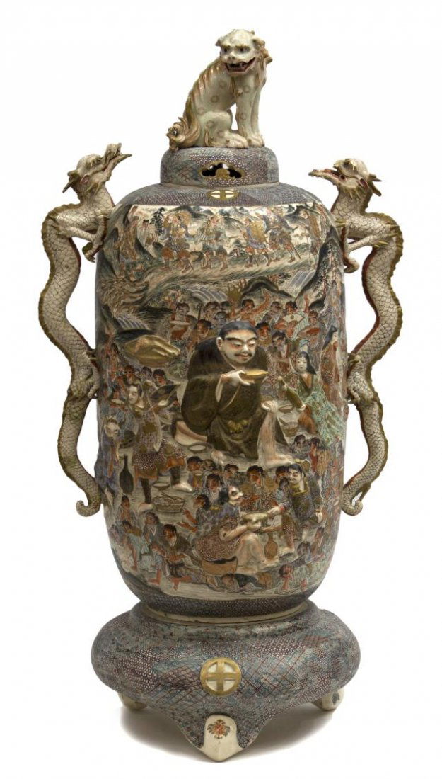 LARGE JAPANESE SATSUMA EARTHENWARE DRAGON URN: Large Japanese Satsuma earthenware covered urn, the pierced dome cover surmounted by a seated foo lion, approached by a pair of dragons mounted has long handles, the cylindrical body with relief and p