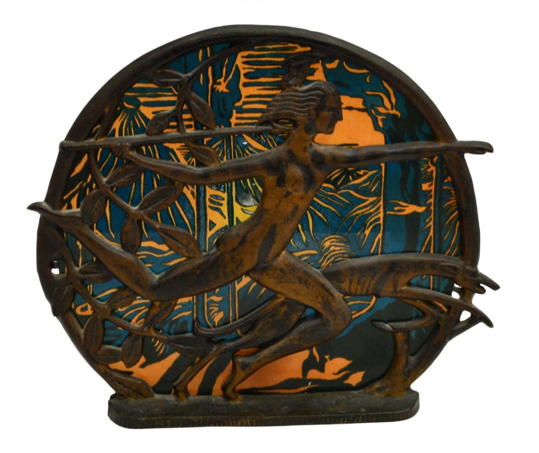 ART DECO IRON FIGURAL ONE-LIGHT TABLE LIGHT: Art Deco one-light iron table light, the pierced circular panel depicting a striding woman holding a spear alongside a great dane, a polychrome painted glass panel of mountains for shade, 11.25"h, 13"