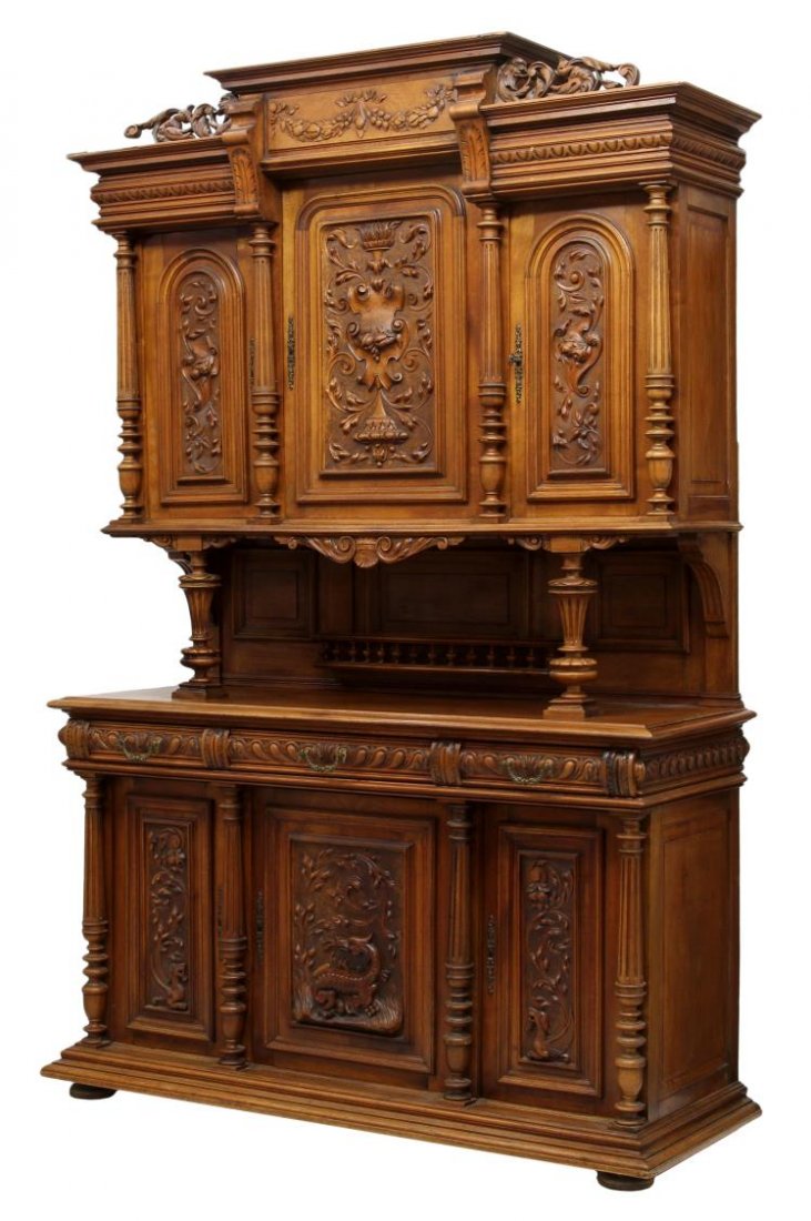 FRENCH HENRI II STYLE CARVED CUPBOARD: French Henri II style walnut cupboard with panels of foliate carved decoration flanked by ribbed columns, late 19th c., a stepped cornice over the carved garland frieze with flanking griffins, the upp