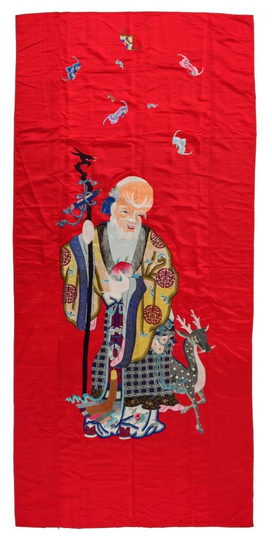 VINTAGE CHINESE SILK FIGURAL EMBROIDERED PANEL: Chinese silk embroidered red satin panel, purchased in Shanghai, c. 1949, bats and auspicious symbols center Shou Lao, the God of Longevity and his companion deer, some staining, 98.25”l, 46.25”w,