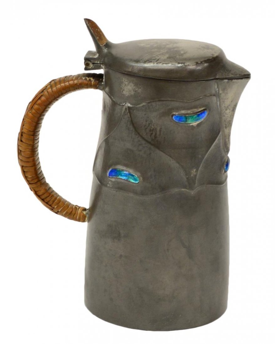 SCARCE LIBERTY & CO. ENAMELED PEWTER FACE JUG: Scarce Liberty & Company 'English Pewter' Tudric face jug, RD 421106, 0278, enameled accents form the eyes and mouth, while the spout served as a nose, rattan woven handle, some surface wear, 6"h, 4.5