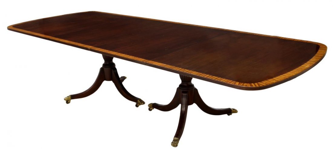 GEORGIAN STYLE MAHOGANY DINING TABLE, 120"L: Ethan Allen Georgian style dining table, late 20th c., mahogany with a contrasting perimeter band, two 24" leaves, rising on two three leg pedestals with brass claw feet on castors, scratches, with le
