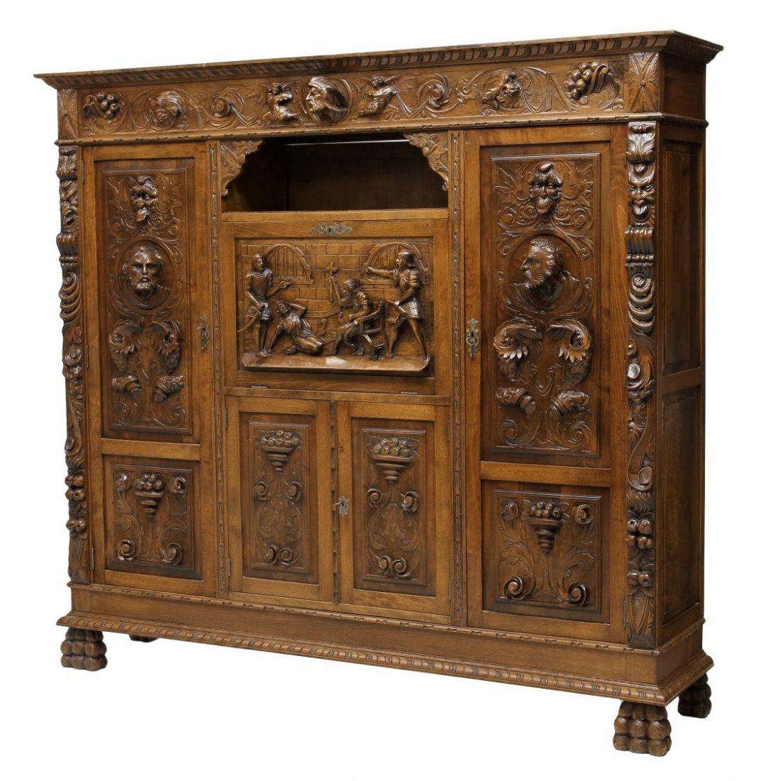 FIGURAL & FLORAL CARVED SPANISH BOOKCASE: Highly carved Spanish bookcase, Barcelona, early 20th c., having relief figural and floral carvings, a central drop front door faced with a religious scene over two drawers, opens to a shelved interio
