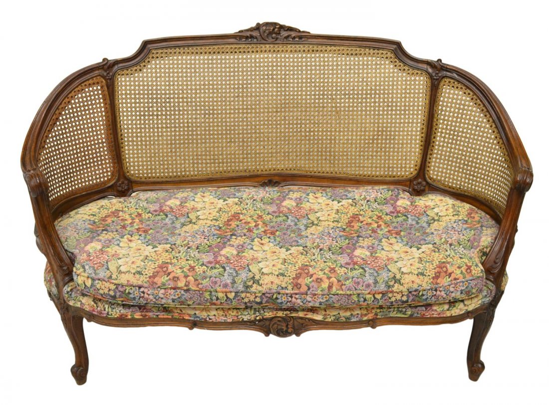 LOUIS XV STYLE CARVED OAK CANE BACK SETTEE: Louis XV style settee, a foliated crest on the curved oak frame enclosing a cane panel, upholstered seat with loose cushion, raised on cabriole legs, ending in a scrolled toe, approx 34.75"h, 52.5"w, 