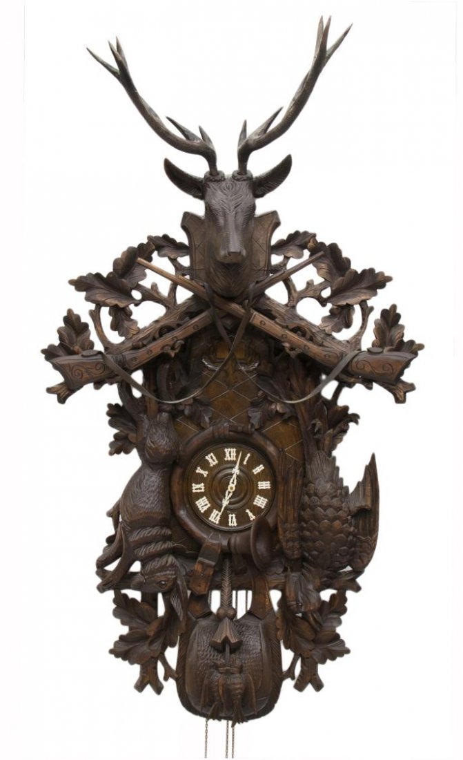 GRAND BLACK FOREST REGULA MUSIC BOX CUCKOO CLOCK: Monumental size German Black Forest Regula music box cuckoo clock, the crown with a carved deer head over crossed rifles with leather slings deer head, at one side a 23"l carved rabbit, the opposite s